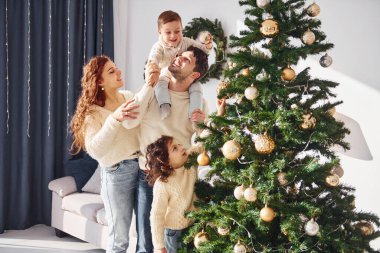 Noel ağacı süslemek. Yeni yılı evde çocuklarıyla kutlayan aileler..