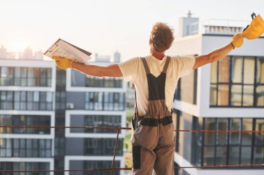 Proje yöneticisi. Gündüz vakti inşaatta üniformalı genç bir adam çalışıyor..