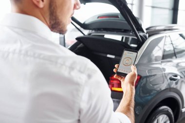 Etiketli ve simgeli telefonları tutan adamın elini yakından izle. Uzaktan kumanda kavramı.