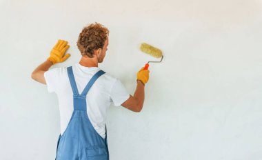Temiz duvarlar. Gündüz vakti inşaatta üniformalı genç bir adam çalışıyor..