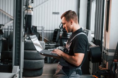 Üniformalı adam otomobil servisinde çalışıyor..