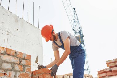 Üniformalı genç inşaat işçisi tamamlanmamış binada meşgul..