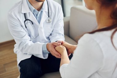 Hastanın elini tutmak. Klinikte beyaz önlüklü profesyonel doktor var..