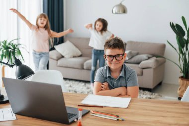 Çocuk masanın yanında oturuyor. Çocuklar gündüz vakti evlerinde eğleniyorlar..