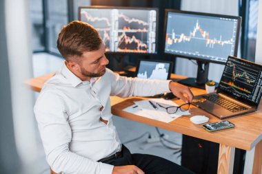 Resmi kıyafetlerle. Genç işadamı birden fazla ekranla ofiste..