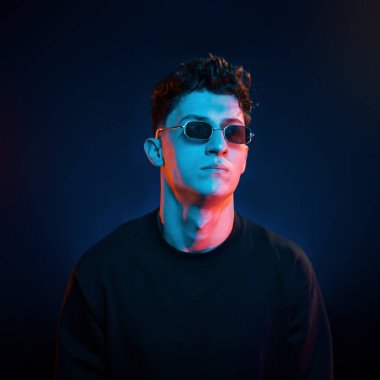 Şık bir görünüş. Neon ışıkları. Genç Avrupalı adam karanlık stüdyoda..