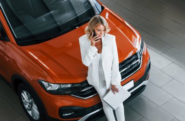 Elinde telefonla hem de. Resmi giyinmiş bir kadın otosalon 'da içeride..