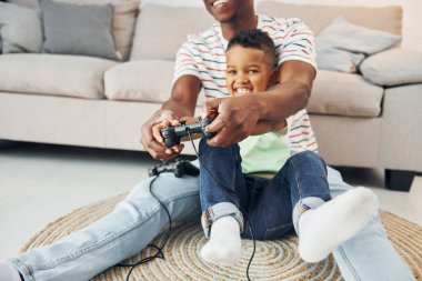 Elinde joysticklerle. Afrikalı Amerikalı baba ve küçük oğlu evde..