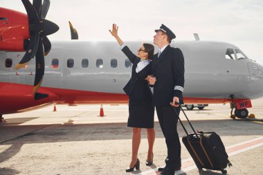 Pilot ve hostes. Havaalanı ve uçak işçileri resmi giysiler içinde dışarıda birlikte duruyorlar..
