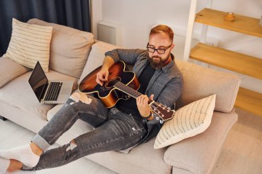 Pratik yaparken iyi vakit geçiriyorum. Gündelik giysiler içinde ve akustik gitarlı bir adam içeride..