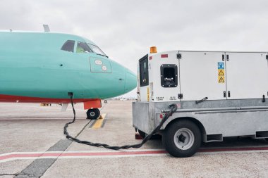Yakınlarda bir araç var. Turbo pervaneli uçak gündüz vakti piste park etmiş..
