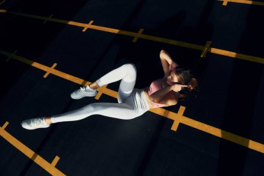 Siyah renkli zeminde. İnce vücutlu güzel bir kadın spor salonunda..