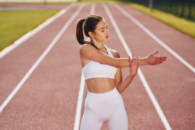 Ayakta ve pratik yaparak. Spor elbiseli genç bayan dışarıda egzersiz yapıyor..