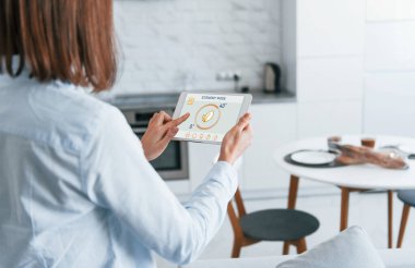 Modern teknolojiler. Evin içini kontrol eden bir kadının arka görünüşü..