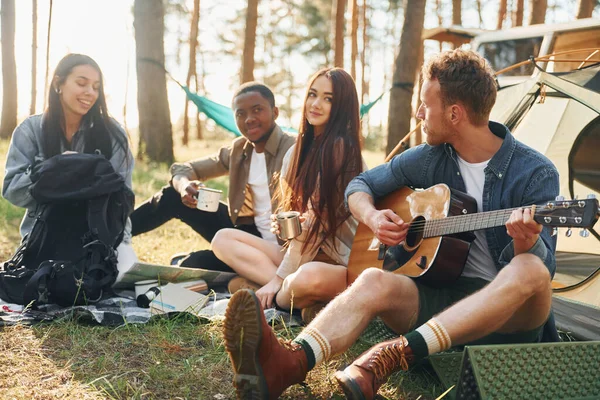 Hombre Toca Guitarra Grupo Jóvenes Viaja Juntos Bosque Durante Día — Foto de Stock