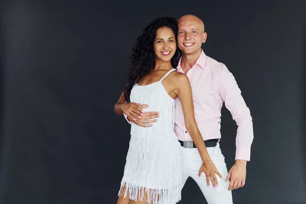 Dancing against black background. Cheerful couple is together indoors.