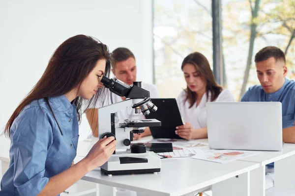 Χρησιμοποιώντας Μικροσκόπιο Ομάδα Νέων Γιατρών Εργάζεται Μαζί Στο Σύγχρονο Γραφείο — Φωτογραφία Αρχείου