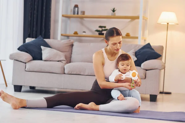 在瑜伽垫上妈妈和她的小女儿在家里 — 图库照片