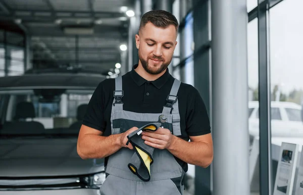 Wycieram Ręce Człowiek Mundurze Pracuje Autosalonie Dnia — Zdjęcie stockowe