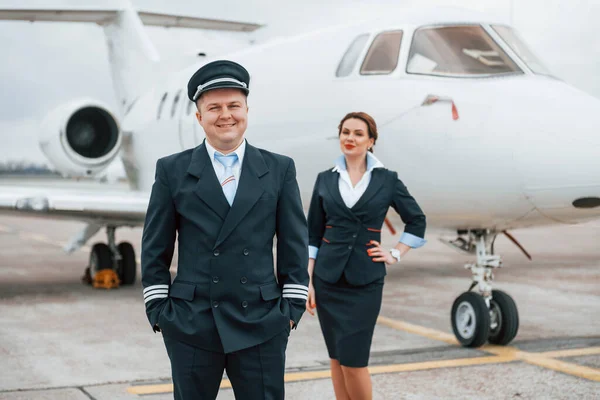 Man with woman. Aircraft crew in work uniform is together outdoors near plane.