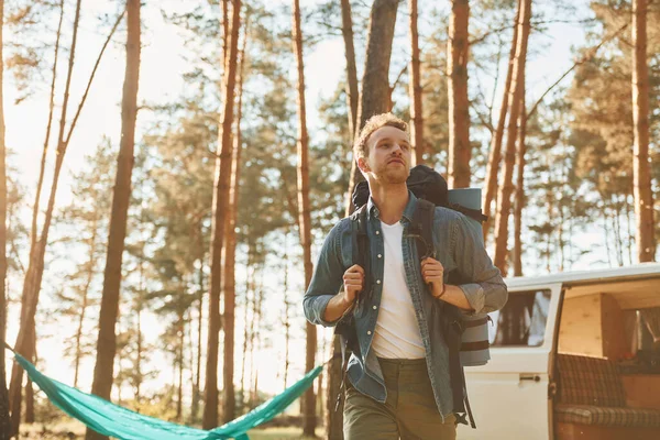 Near car and camp. Man is traveling alone in the forest at daytime at summer.