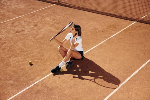 地面に座って 女子テニス選手は昼間はコートにいる — ストック写真
