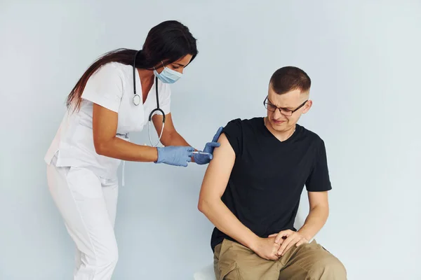Man is nervous. Doctor in uniform making vaccination to the patient.