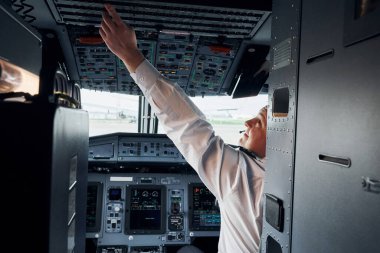Resmi kıyafetli pilot kokpitte oturur ve uçağı kontrol eder..
