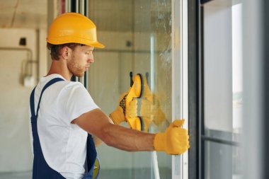 İşinde usta. Gündüz vakti inşaatta üniformalı genç bir adam çalışıyor..