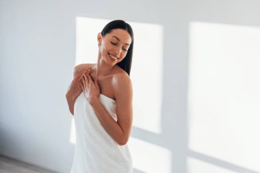 Beyaz duvarlı bir odada. İnce vücutlu beyaz kadın gündüz vakti evdedir..