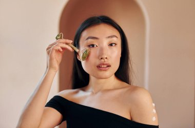 Deri temizleme aleti kullanıyor. Genç ciddi Asyalı kadın içeride duruyor..