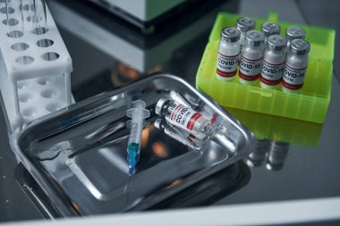 Temiz yüzey. Laboratuvardaki test tüplerindeki COVID-19 aşısının görüntüsünü kapat..