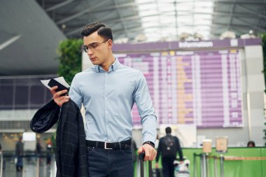 Resmi giyinmiş genç bir erkek yolcu havaalanında..