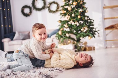 Uzanmak ve oynamak. Küçük kız ve erkek kardeş noel süsleme odasında beraberler..