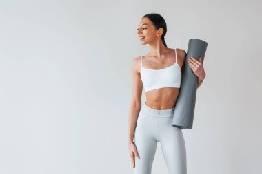 Yoga minderiyle. Stüdyoda iç çamaşırlı, zayıf vücutlu bir kadın var..