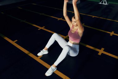 Elleri ağırdır. İnce vücutlu güzel bir kadın spor salonunda..