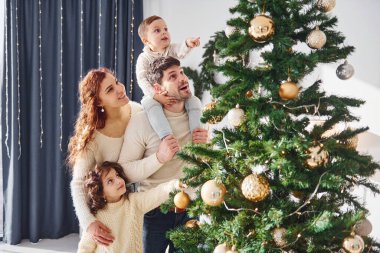 Noel ağacı süslemek. Yeni yılı evde çocuklarıyla kutlayan aileler..