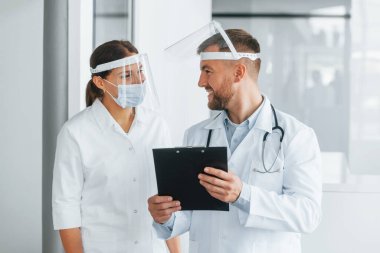Belgelerle çalışıyorum. Beyaz önlüklü iki doktor klinikte..