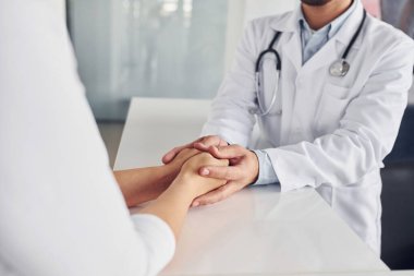 Müşteriyi ellerinden tutmak. Klinikte beyaz önlüklü profesyonel doktor var..