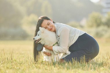 Evcil hayvanı kucaklamak. Köpeğiyle bir kadın güneşli bir günde sahada eğleniyor..