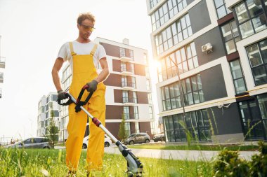 Bir kişi. Bahçede çimleri çim biçen bir adam var..