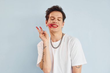 Genç eşcinsel adam stüdyoda duruyor ve kameraya poz veriyor. Hareketleri gösterir.