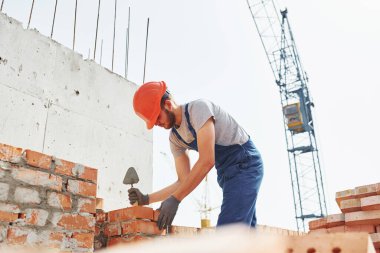 Üniformalı genç inşaat işçisi tamamlanmamış binada meşgul..