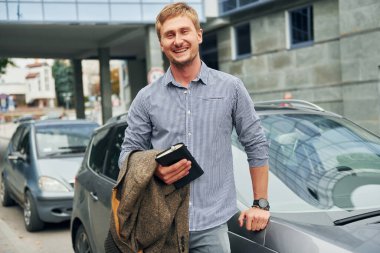 Elinde not defteriyle. Gündüz vakti şehirde gezen bir adam..