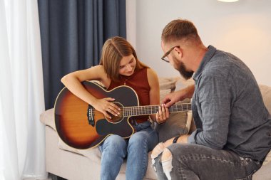 Özel ders. Gitar öğretmeni enstrümanı genç bir kadına nasıl çalacağını gösteriyor..