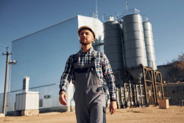 Doğal ışıklandırma. Üniformalı inşaat işçisi fabrikanın yakınında..