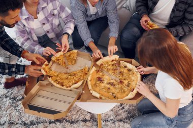 Lezzetli pizza yiyorum. Bir grup arkadaş içeride parti veriyor..