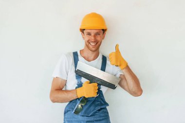 Temiz duvarlar. Gündüz vakti inşaatta üniformalı genç bir adam çalışıyor..