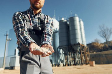 Toprağı tutarak. Üniformalı inşaat işçisi fabrikanın yakınında..