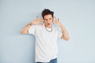 Genç eşcinsel adam stüdyoda duruyor ve kameraya poz veriyor. Kırmızı renkli dudaklar..